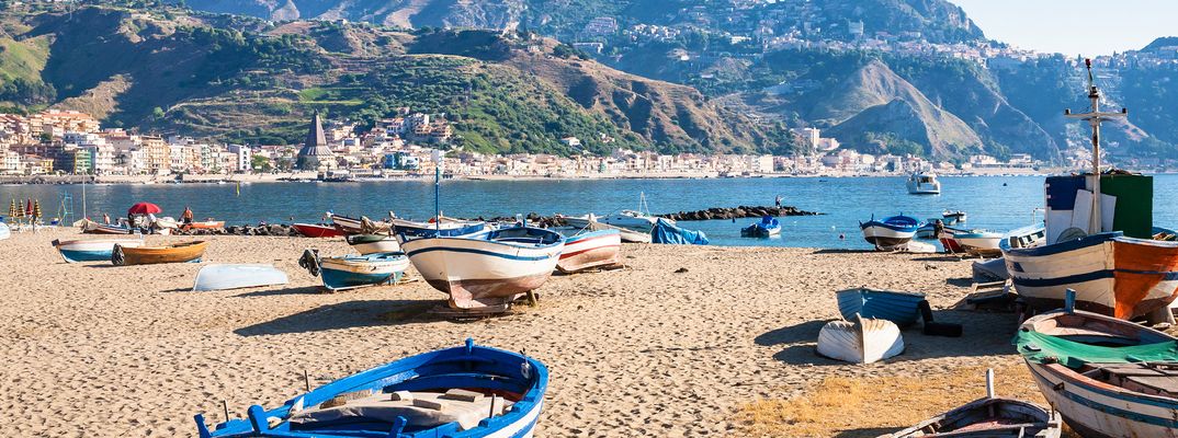 Strand von Giardini Naxos mit Booten und Blick auf die Berge