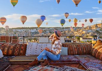 Reisende sitzen auf einer Terrasse und frühstücken mit Blick auf Ballons