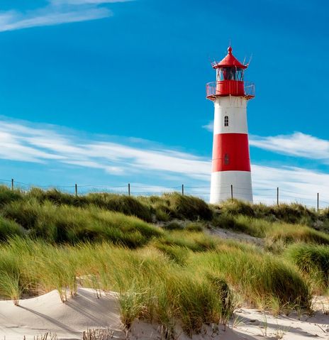 Roter Leuchtturm auf Sylt vor blauem Himmel