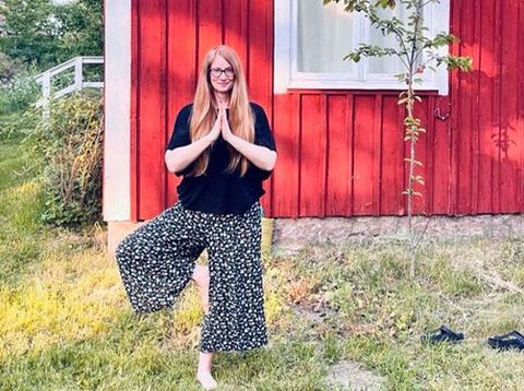 Berge & Meer-Mitarbeiterin Alessia macht Yoga vor einem Holzhaus in Schweden