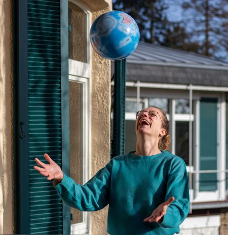 Mitarbeiterin Manuela hat Spaß mit einem Wasserball als Globus