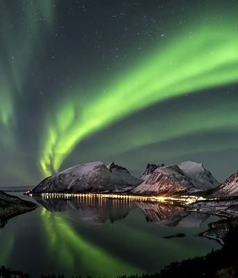 Nordlichter über verschneiten Bergen und einem Fjord