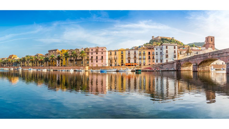 Blick vom Meer aus auf den Hafen von Bosa auf Sardinien mit Häuserfront, Booten und Brücke