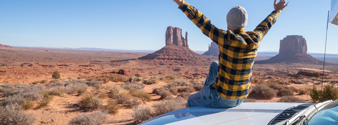 Reisender neben einem Mietwagen mit Blick auf das Monument Valley in den USA