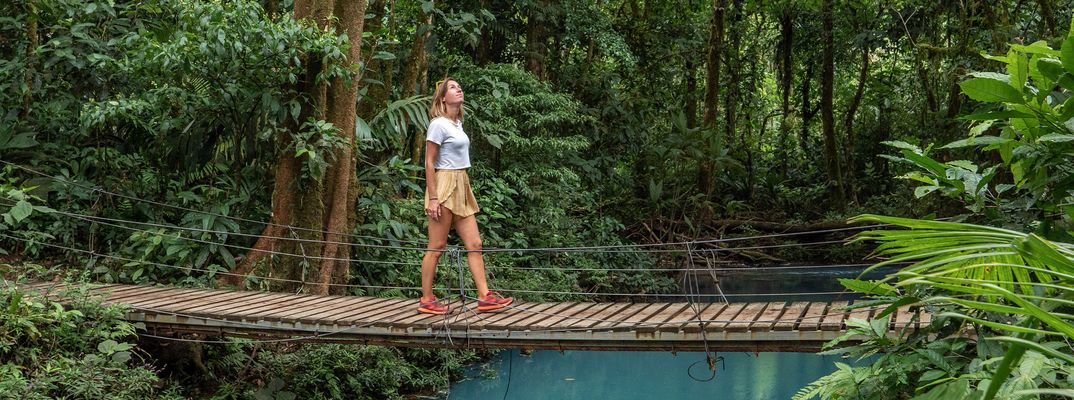 Frau steht auf einer Hängebrücke über dem Regenwald von Costa Rica