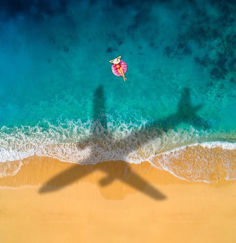 Flugzeugschatten am Strand über Frau im Meer