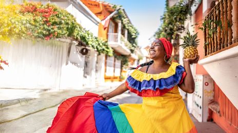 Eine fröhliche Frau in traditioneller kolumbianischer Tracht tanzt auf einer Straße in Cartagena