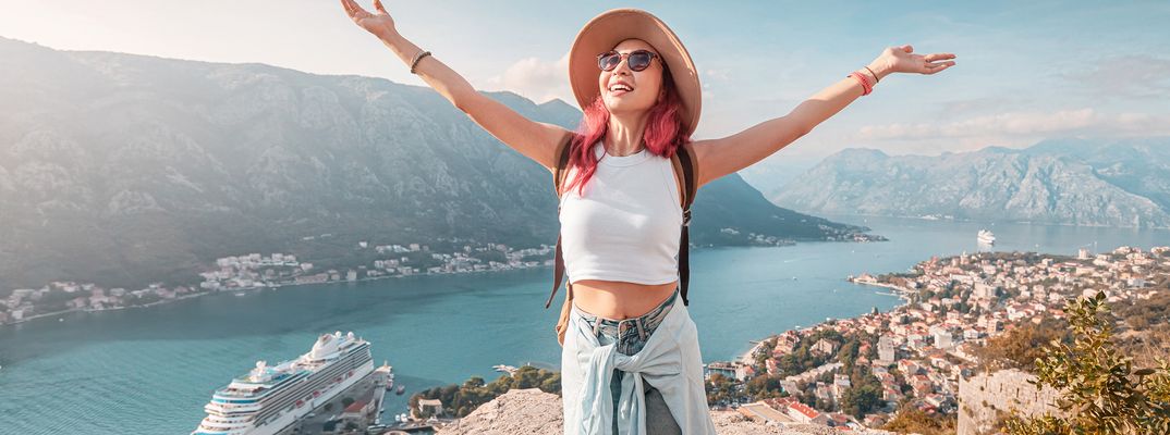 Frau mit ausgestreckten Armen auf einem Felsen vor der Bucht von Kotor