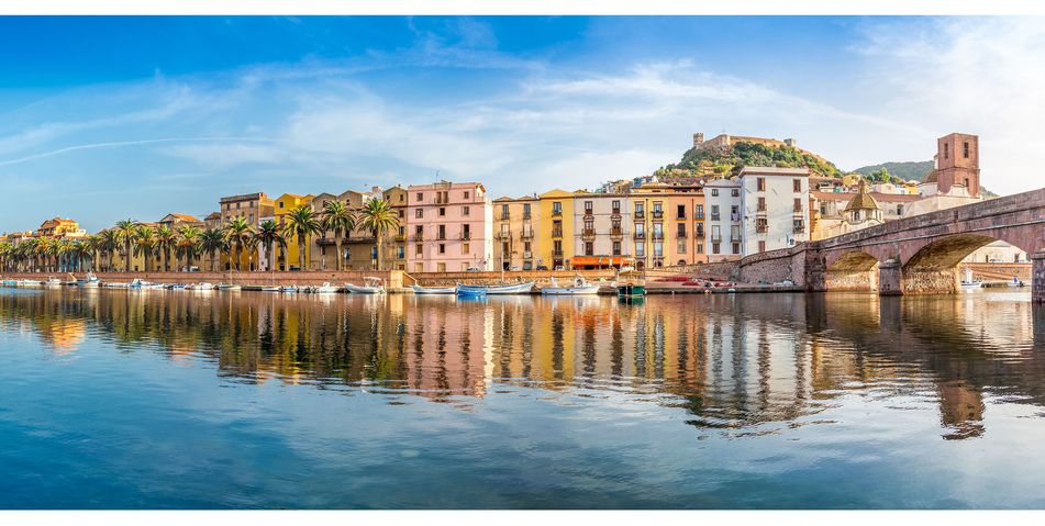 Blick vom Meer aus auf den Hafen von Bosa auf Sardinien mit Häuserfront, Booten und Brücke