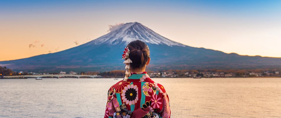 Japanische Frau steht mit dem Rücken zur Kamera am See und schaut auf den Fuji in Japan