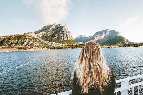 Eine Frau die an Bord eines Schiffes ist und auf Berge in Norwegen schaut