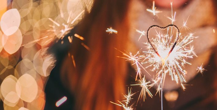 Junge Frau hält Wunderkerze in der Hand und lächelt in festlicher Stimmung