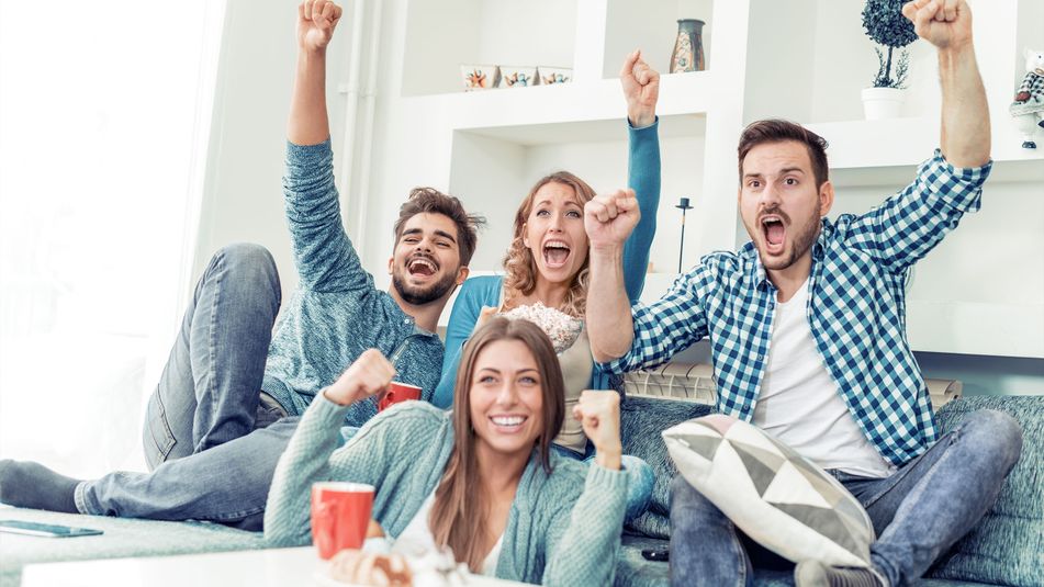 Gruppe von Freunden im Wohnzimmer jubelt