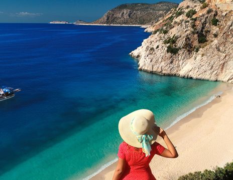 Frau mit Sonnenhut blickt auf eine Bucht an der türkischen Küste