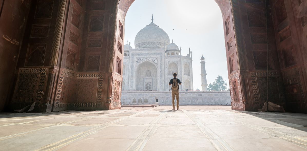 Mann steht im Torbogen mit Blick auf den Taj Mahal
