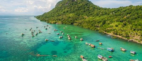 Tropische Küste auf Borneo mit türkisfarbenem Wasser, Booten und Dschungel