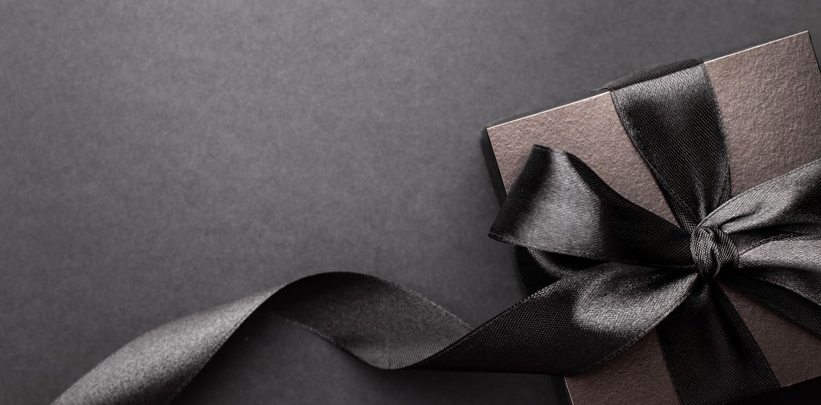 Schwarze Geschenkbox mit schwarzem Band auf dunklem Hintergrund