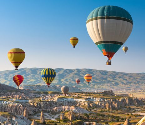 Heißluftballons steigen über Felsformationen in Kappadokien bei Sonnenaufgang