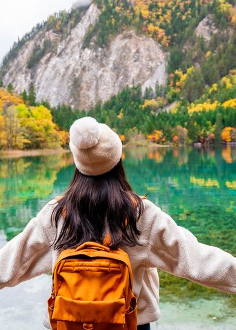 Frau schaut auf eine Herbstlandschaft im Jiuzhaigou-Nationalpark in Sichuan, China