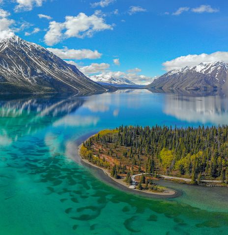 Flusslandschaft im Yukon mit smaragdgrünem Wasser und bewaldeten Hügeln