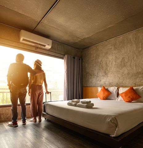 Paar steht Hand in Hand im Hotelzimmer und blickt durch das Fenster