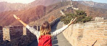 Touristin hebt die Arme auf der Chinesischen Mauer