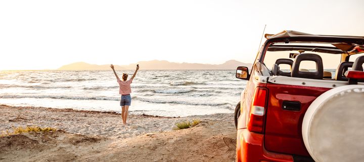 Frau mit einem Auto am Strand