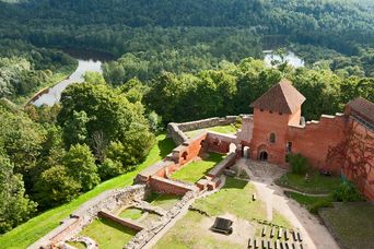Burg Sigulda in Lettland umgeben von grünen Wäldern und hügeliger Landschaft