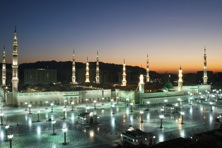 Moschee in Medina bei Nacht mit beleuchteten Minaretten und weitem Vorplatz