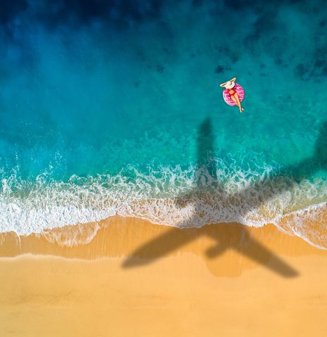 Flugzeug fliegt über das Meer und wirft einen Schatten