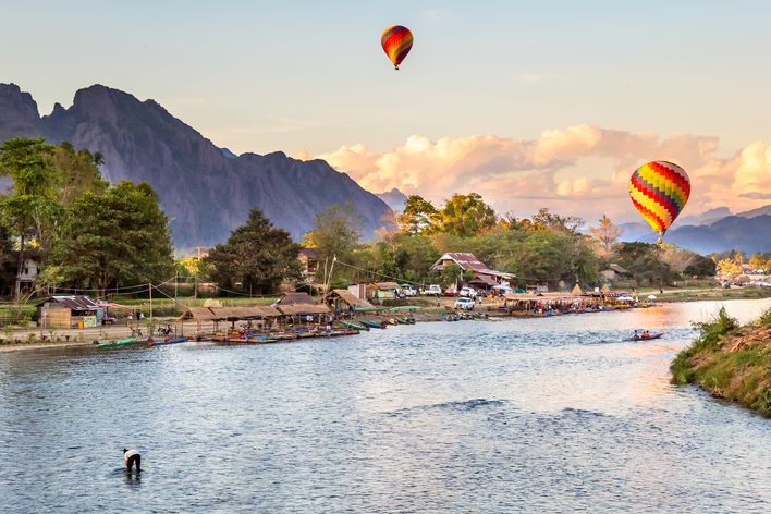 Flusslandschaft bei Vang Vieng mit Bergen und bunten Heißluftballons