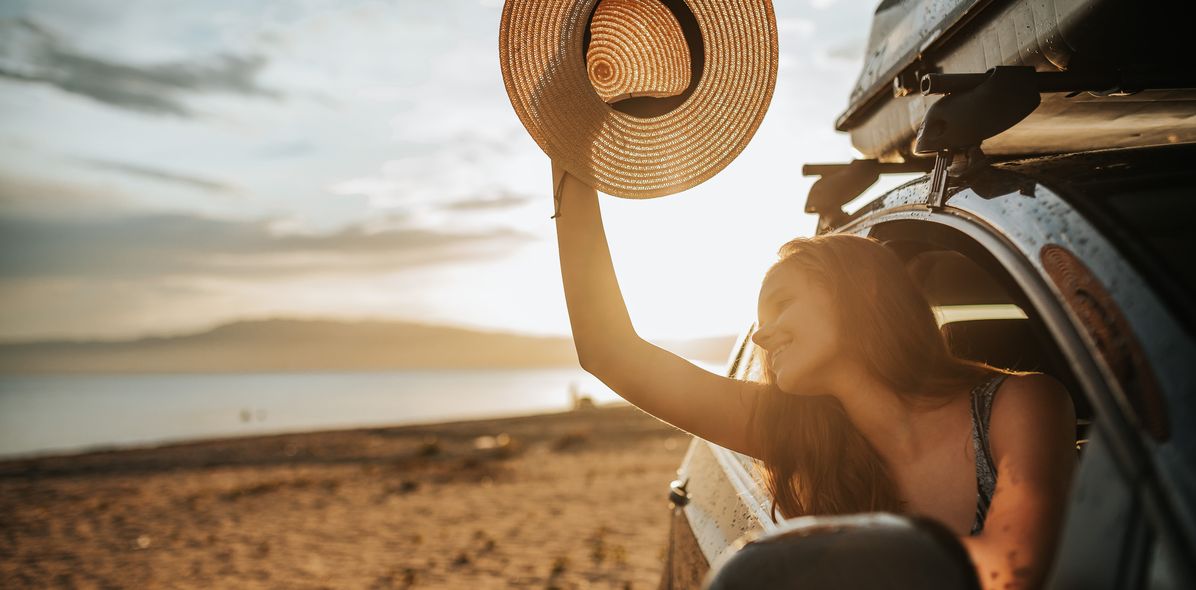 Frau mit Sonnenhut im Auto