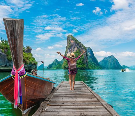 Frau neben einem Boot mit Blick auf die Küste Thailands