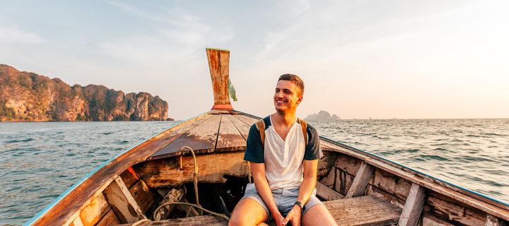 Mann sitzt lächelnd in einem Longtail Boot in Thailand