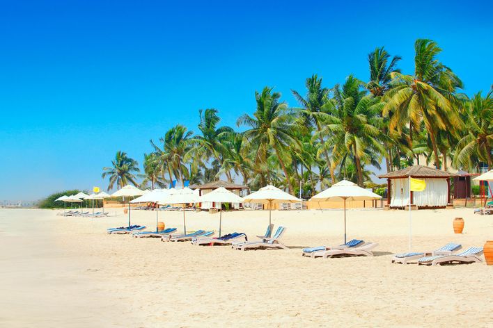 Palmenstrand von Salalah im Oman mit Liegen, türkisfarbenem Meer und Sonne