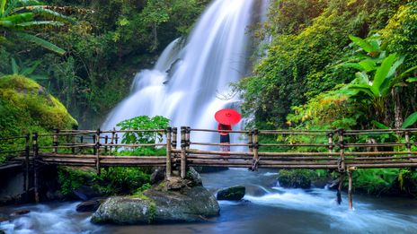 Eine Frau vor einem Wasserfall in der Region Chiang Mai