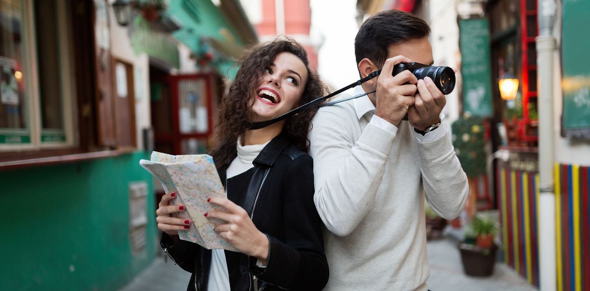 Junges Paar spaziert lachend durch eine bunte Altstadtstraße