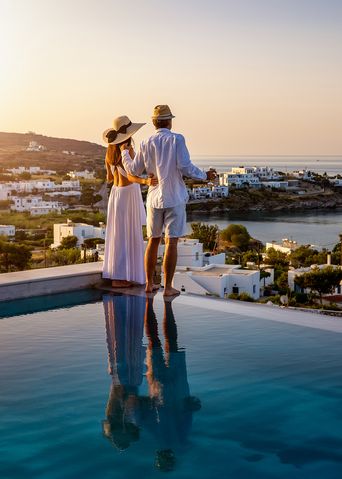 Paar steht am Infinity-Pool und schaut über die Landschaft bei goldenem Licht