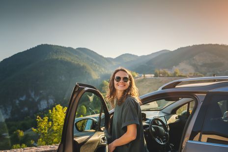 Frau steigt lächelnd aus dem Auto 