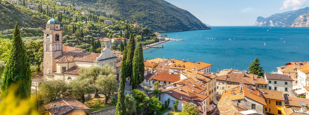 Blick auf Torbole am Gardasee mit Altstadt, Kirche, grünen Hügeln und Gardasee im Hintergrund