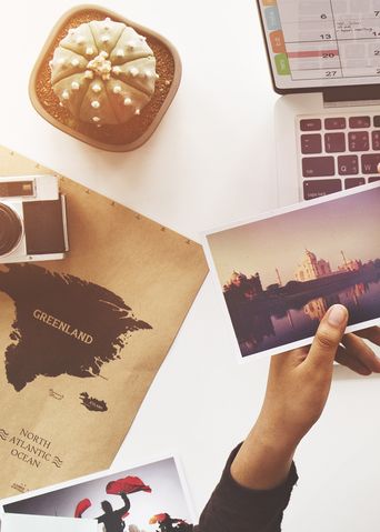 Person mit Postkarte vor dem Laptop