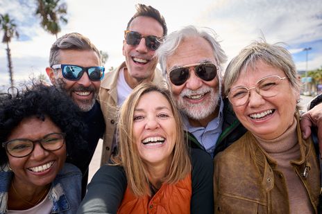 Freundesgruppe macht lachend Selfie im Freien bei Sonnenschein