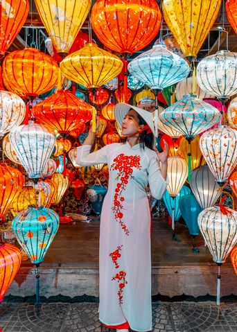 Frau im Ao Dai vor bunten Laternen in der Altstadt von Hoi An