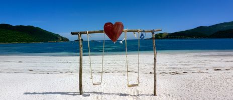 Holzschaukel mit rotem Herz am weißen Sandstrand von Tanjung Aan Beach auf Lombok
