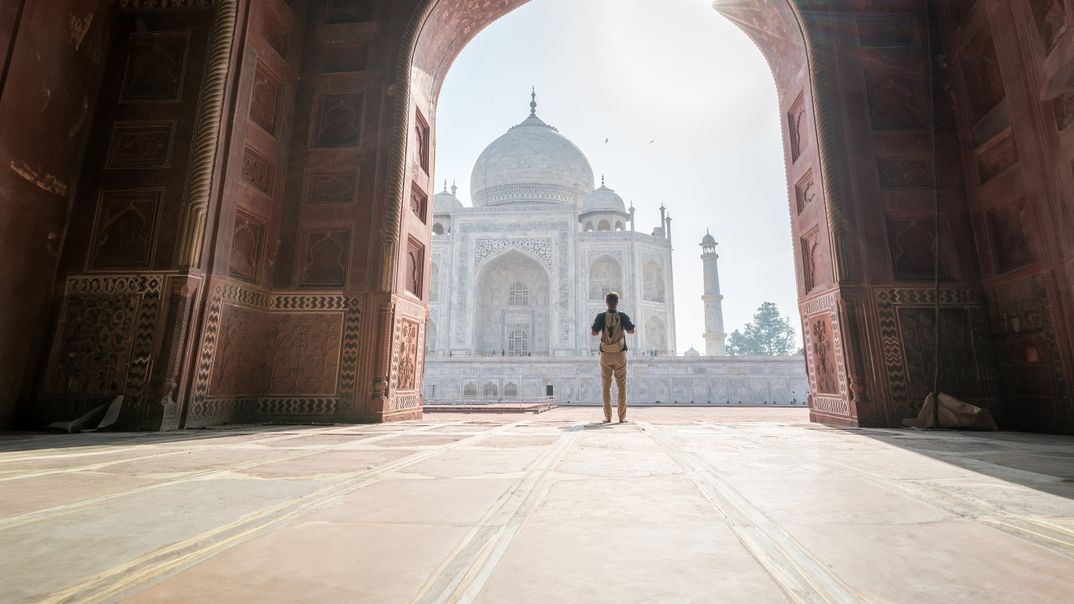 Mann steht im Torbogen mit Blick auf den Taj Mahal