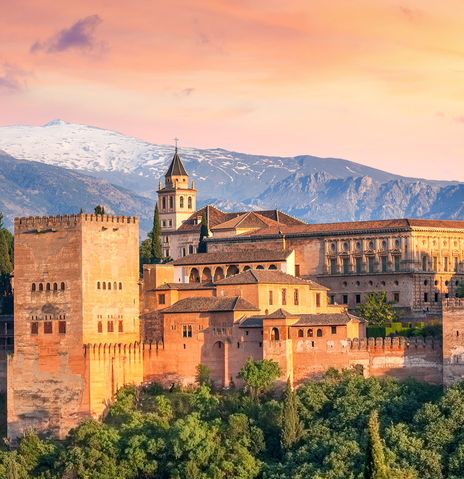 Alhambra in Granada im warmen Licht des Sonnenuntergangs vor der schneebedeckten Sierra Nevada