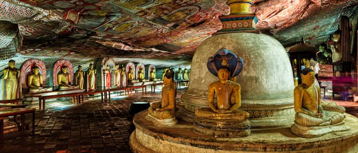 Innenansicht des Dambulla-Höhlentempels mit goldenen Buddha-Statuen und farbenprächtigen Wandmalereien