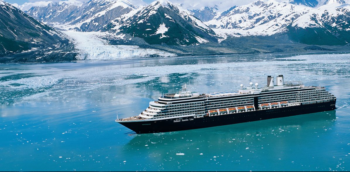 Ein Kreuzfahrtschiff der Holland America Line fährt zwischen Eisschollen und schneebedeckten Bergen in Alaska.