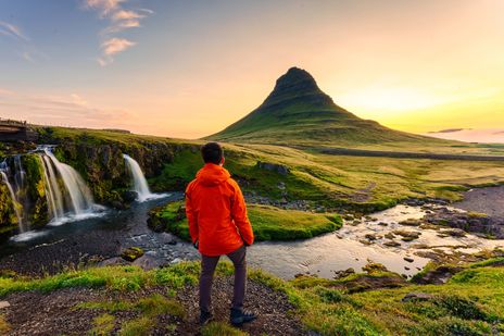 Mann steht am Kirkjufell Wasserfall