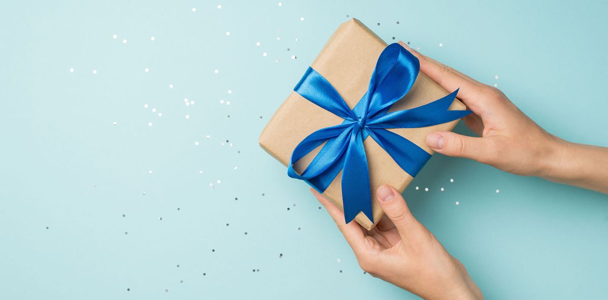 Mensch hält eingepacktes Geschenk in den Händen